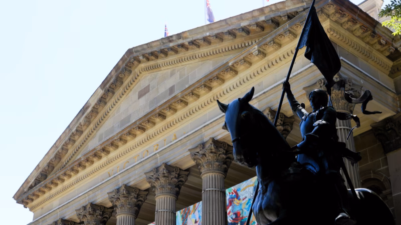 State Library Victoria Melbourne exterior facade with neoclassical columns Victoria inscription and Joan of Arc equestrian statue in foreground