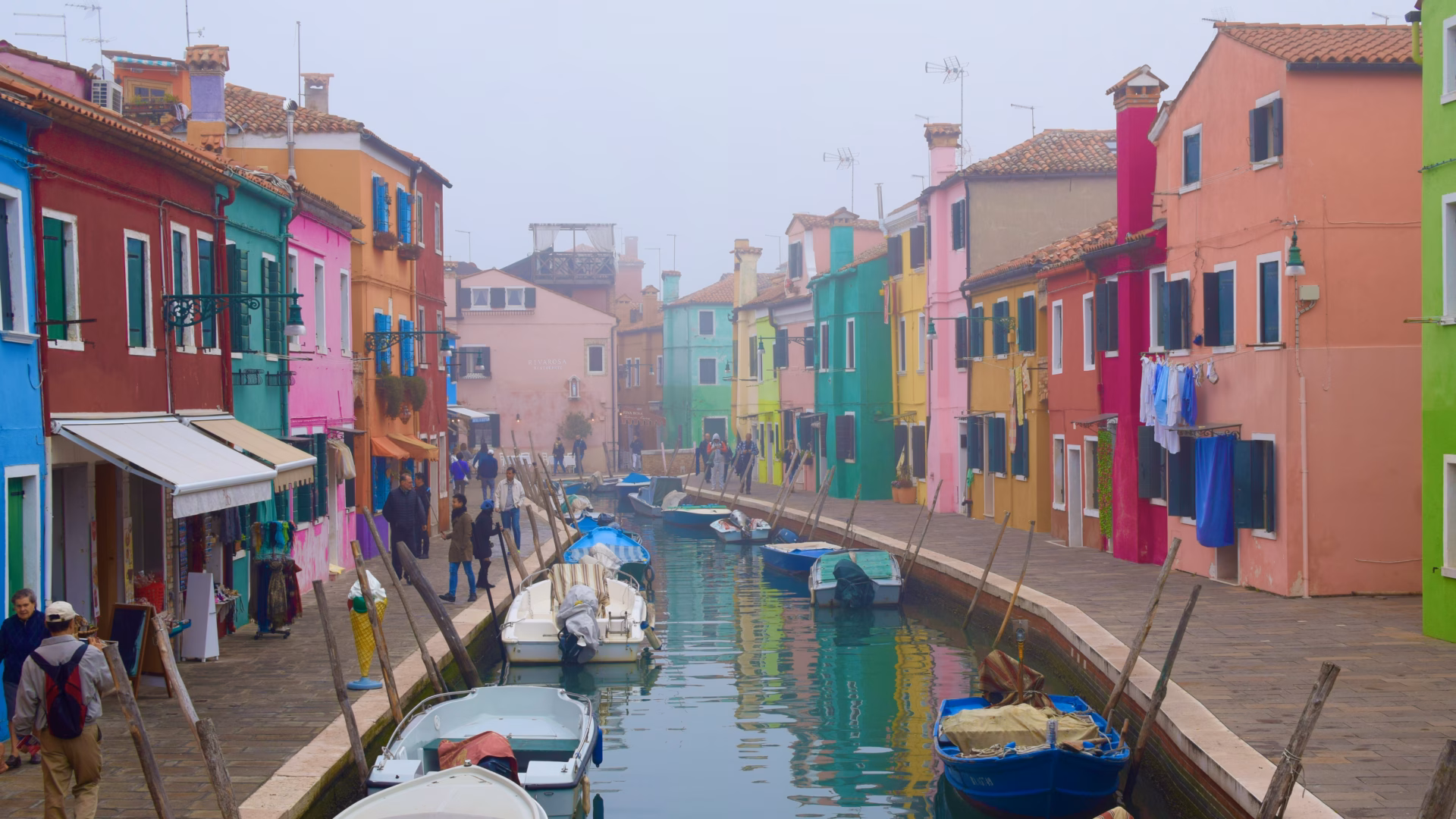 Burano island rainbow colorful houses lining canal with boats in November fog