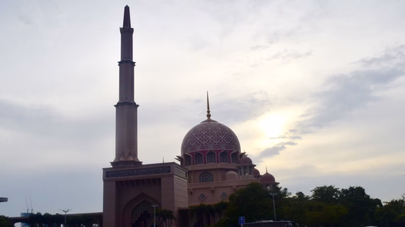 Masjid Putra, the Pink Mosque of Putrajaya, photographed at dusk with its tall minaret and rose-tinted dome glowing against a dramatic cloudy sky