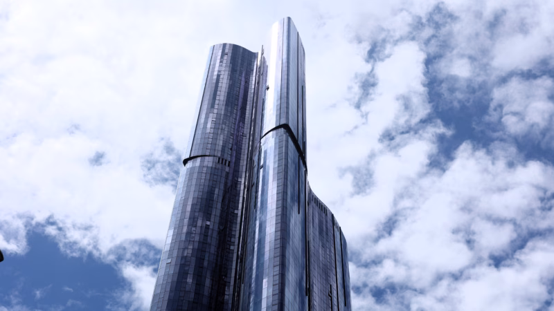 Looking straight up at the Ritz-Carlton Melbourne twin glass skyscraper towers against blue sky and clouds