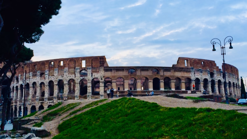 Colosseum Rome exterior wide view from grassy mound in March with green spring grass