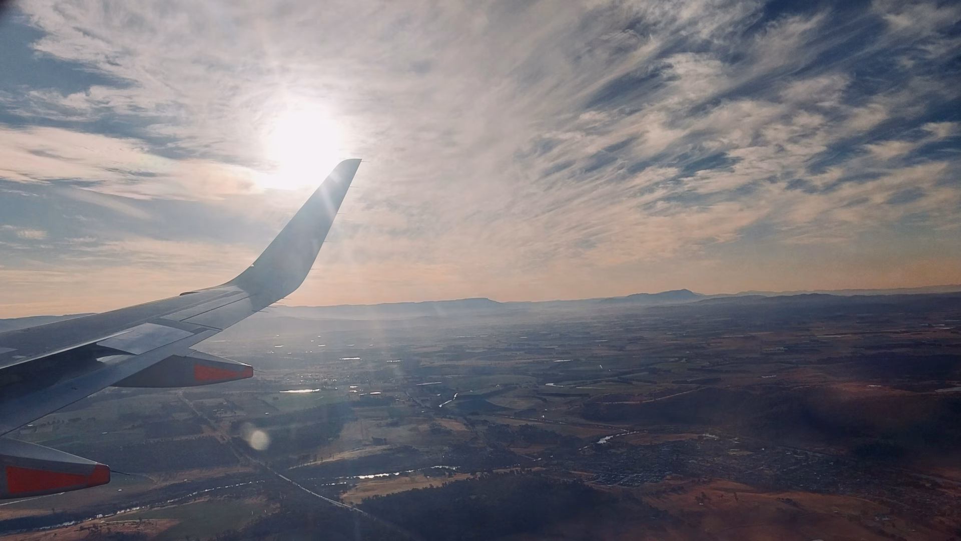 Evening aerial view of Launceston valley with golden sunlight and flat farmland on descent into Launceston Airport