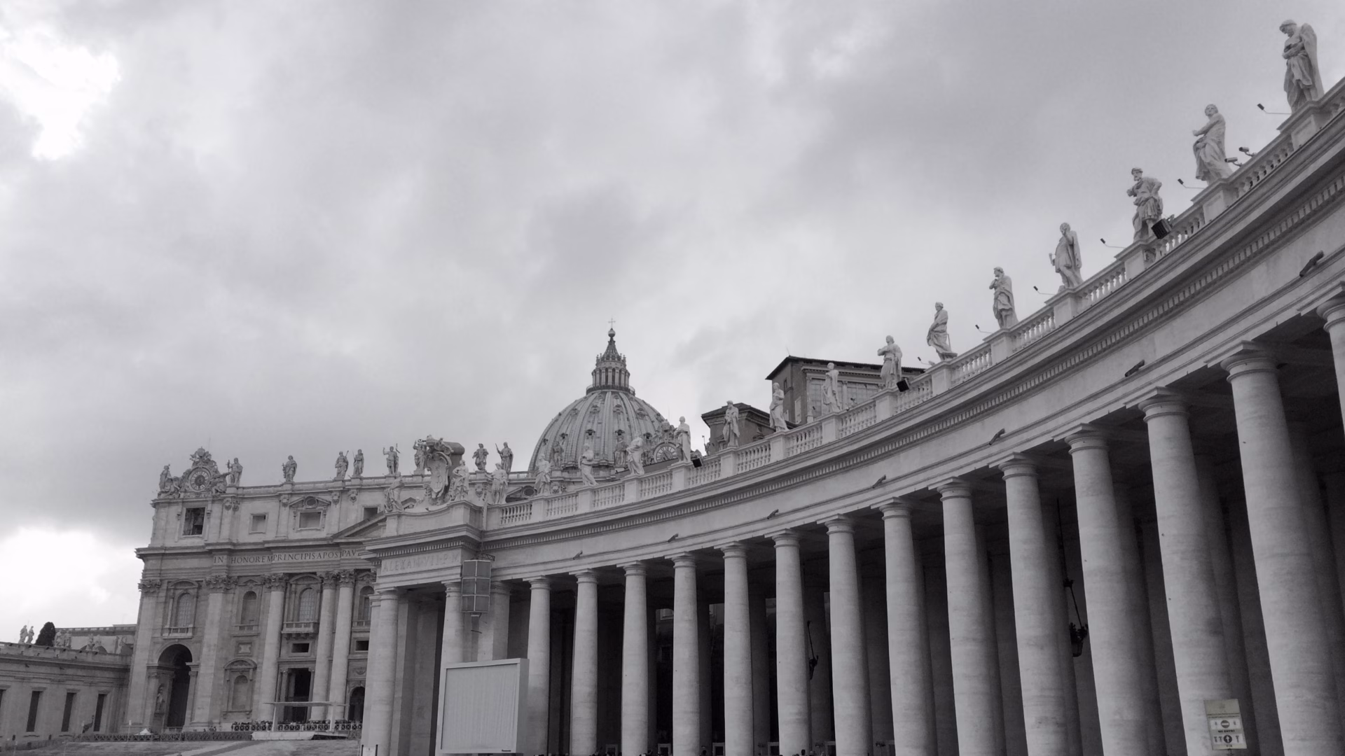 St Peter's Square Vatican City with Egyptian obelisk centred and Bernini colonnades sweeping both sides under dramatic cloudy sky