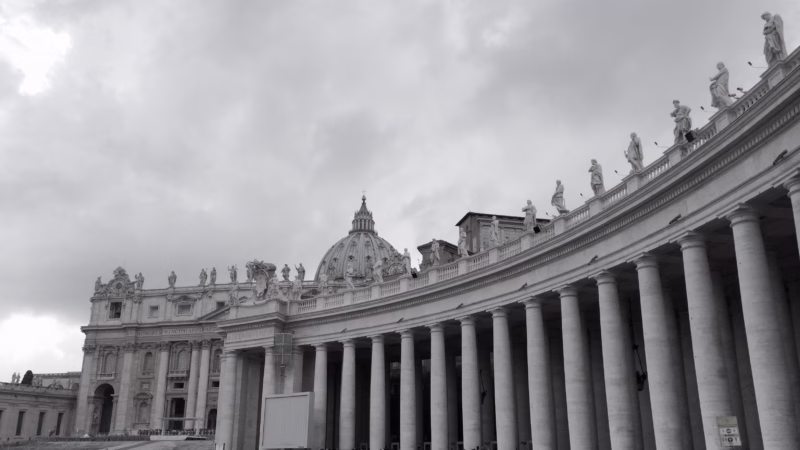 St Peter's Square Vatican City with Egyptian obelisk centred and Bernini colonnades sweeping both sides under dramatic cloudy sky