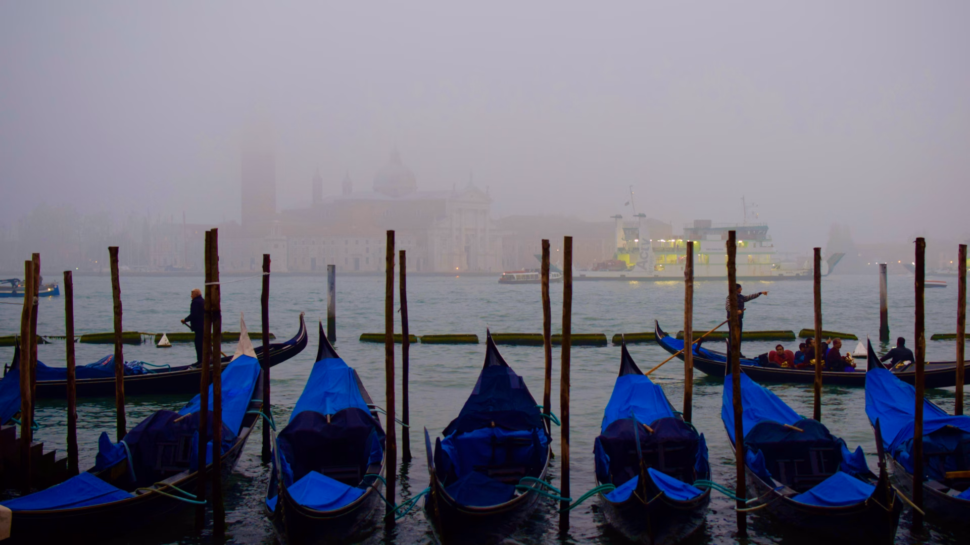 Gondolas moored at St Mark's waterfront in November fog with San Giorgio Maggiore church behind