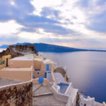 Oia village in Santorini with iconic blue-domed church and white cliffside houses overlooking the caldera