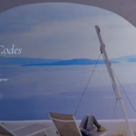 Santorini caldera view through a white arch with sun loungers and the blue Aegean sea