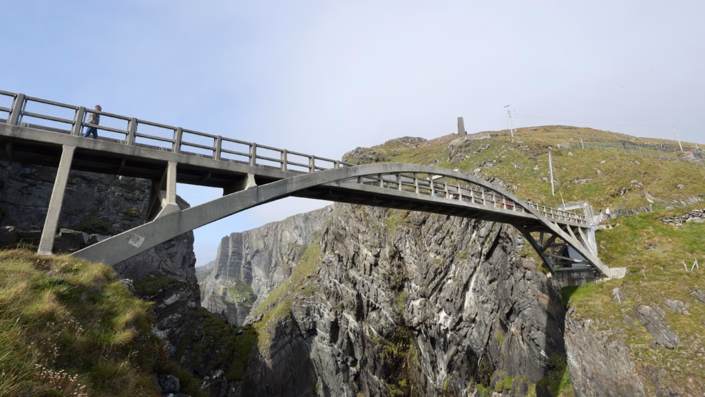 The Mizen Head Bridge arch seen from directly below, soaring overhead with the gorge below and signal station obelisk behind