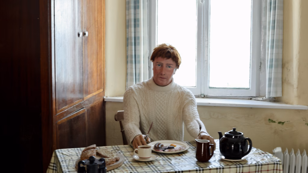 Wax figure of a lighthouse keeper seated at a table with tea and toast inside the Mizen Head Signal Station