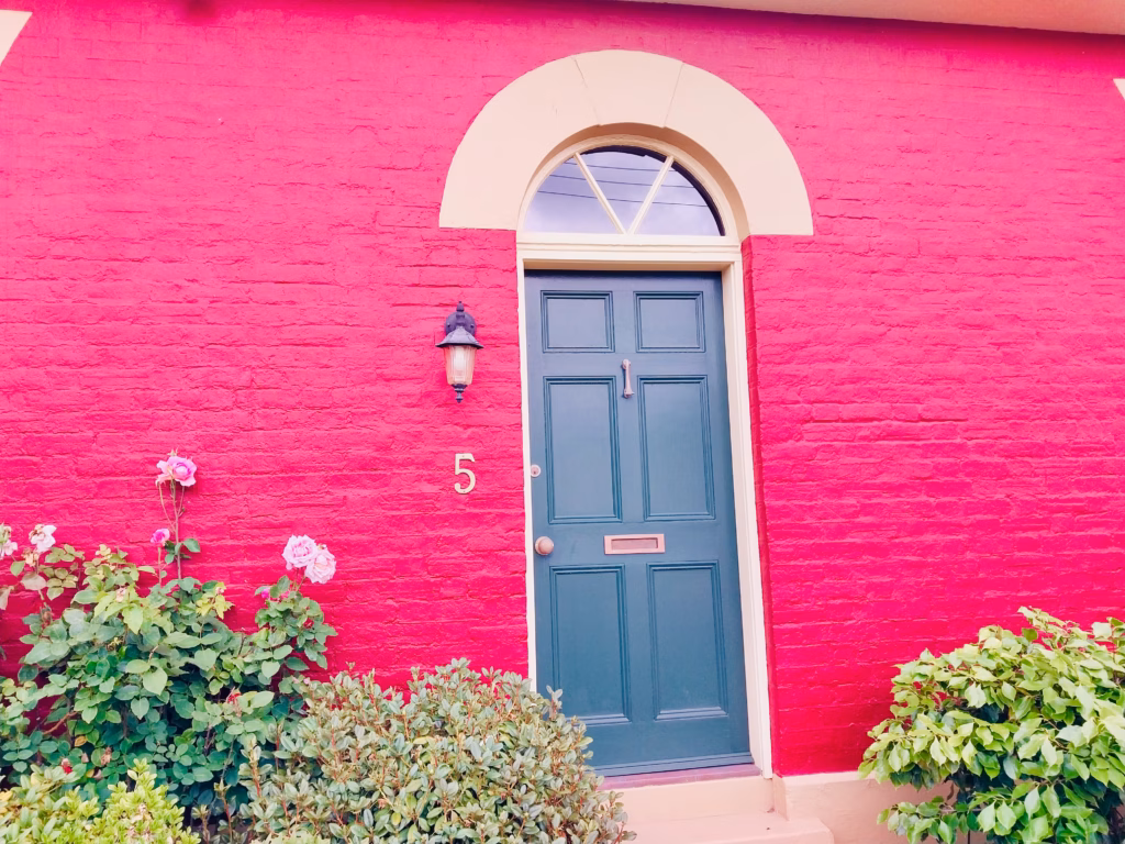 Deep red brick heritage townhouse in Battery Point with a dark green front door and roses