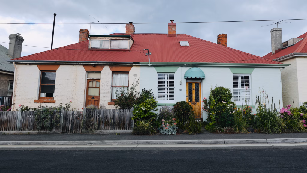Pair of semi-detached pastel cottages in Battery Point with terracotta roof trim and cottage garden