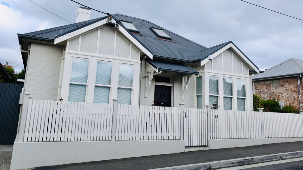 Renovated grey rendered cottage in Battery Point with skylights and a white picket fence