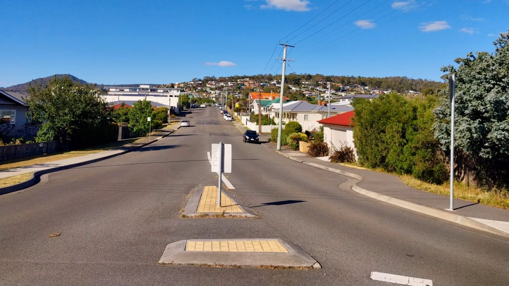 Quiet residential street in Bellerive Hobart sloping downhill with weatherboard homes on both sides