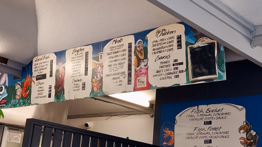 Hand-painted fish and chips menu board at a Constitution Dock food stall in Hobart