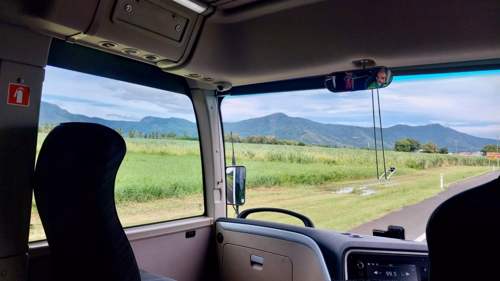 Hotel shuttle bus interior view of cane fields and mountains near Cairns