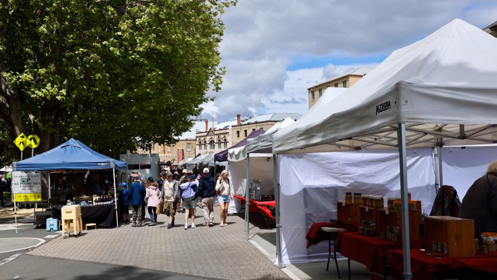 Salamanca Market stalls under trees with the Salamanca Place parking sign, Hobart