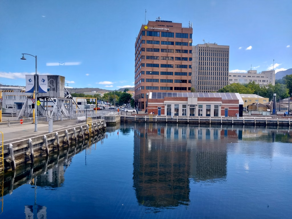 Sullivans Cove Hobart with heritage sandstone government buildings, modern glass architecture, and yachts moored in the foreground