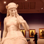 Classical marble sculpture of a seated female figure in a TMAG gallery