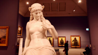 Classical marble sculpture of a seated female figure in a TMAG gallery