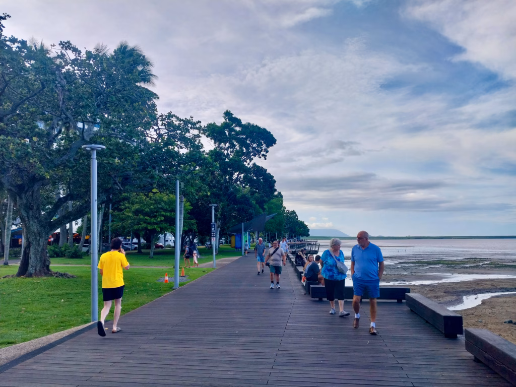 People walking and jogging along the timber boardwalk of the Cairns Esplanade in the early evening