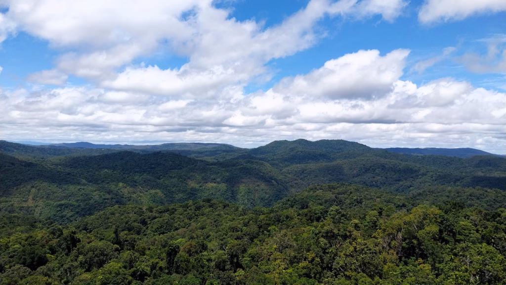 A wide view of rainforest-covered mountains and layered ranges near Cairns under a partly cloudy sky