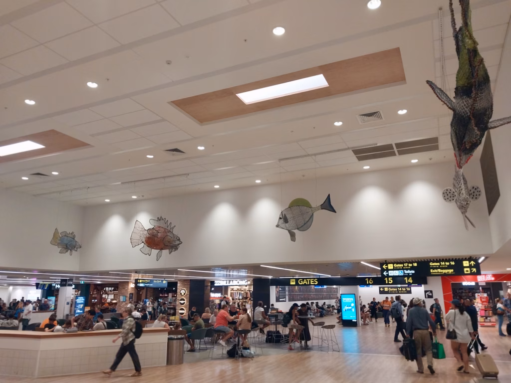 Interior of Cairns Airport domestic terminal near the departure gates, with hanging fish sculptures overhead