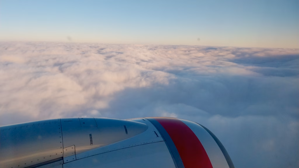 Wing and engine view above clouds in golden late-afternoon light during descent