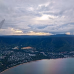 Sunset light over a coastal town on the Cairns Northern Beaches during final descent
