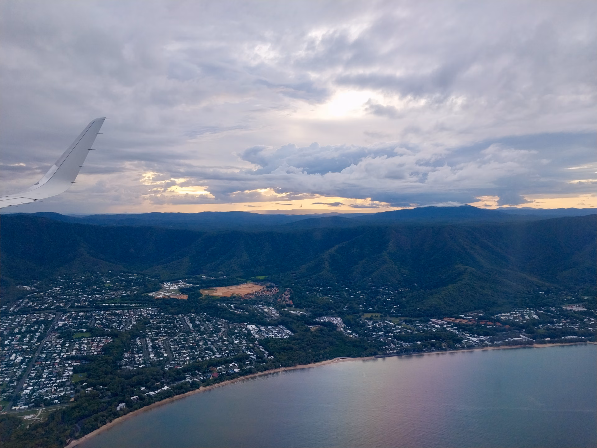 Sunset light over a coastal town on the Cairns Northern Beaches during final descent