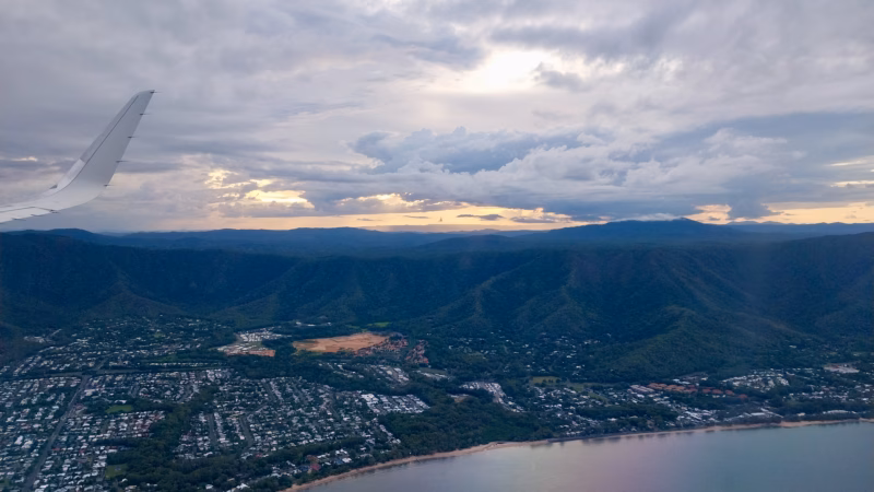 Sunset light over a coastal town on the Cairns Northern Beaches during final descent