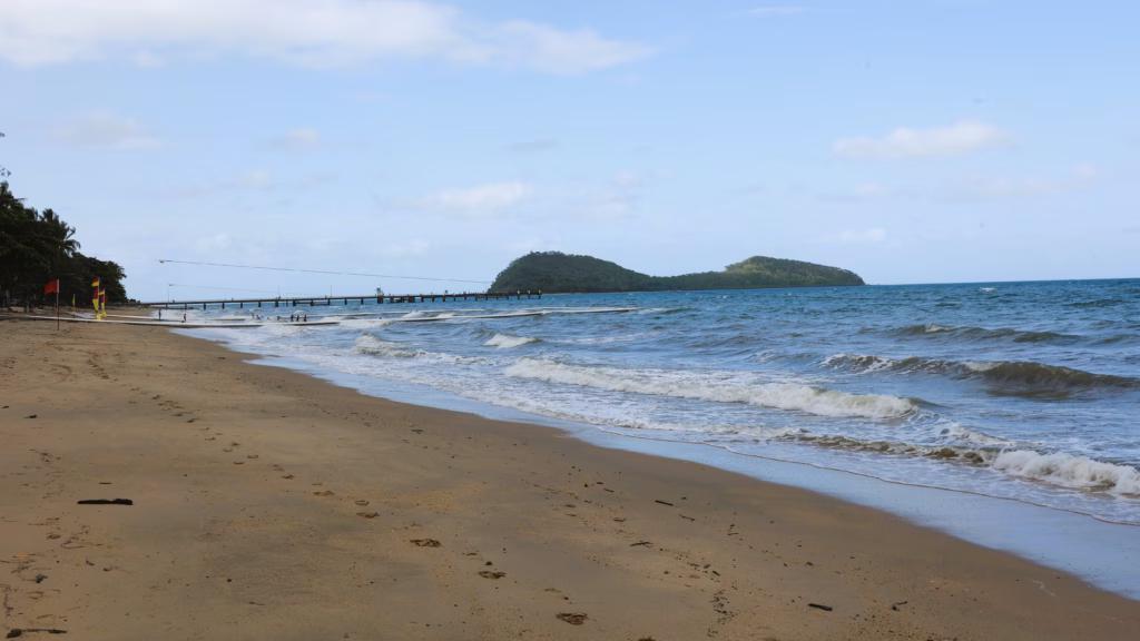 Palm Cove's jetty extending into the water, with lifeguard flags marking the swimming enclosure