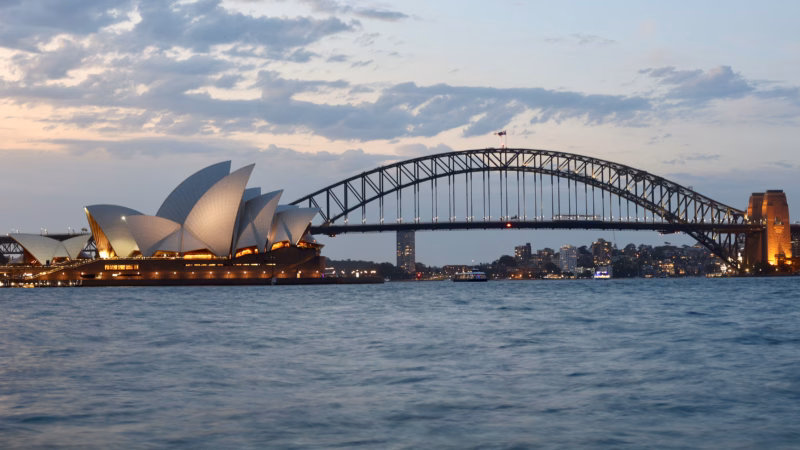 Sydney Opera House and Harbour Bridge seen together across the harbour at dusk