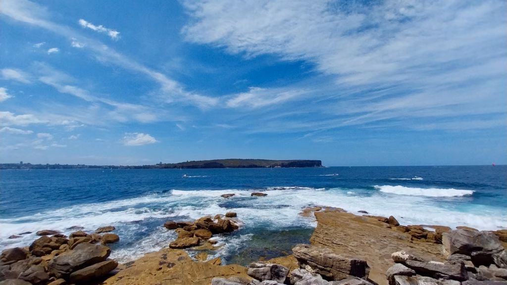 Rocky coastline and ocean waves at Watson's Bay, Sydney, with South Head in the distance