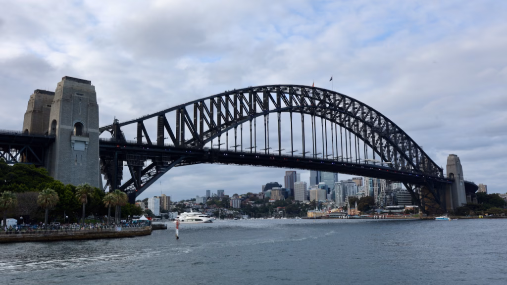 Sydney Harbour Bridge from the water on an overcast day, Luna Park visible small and distant on the far side