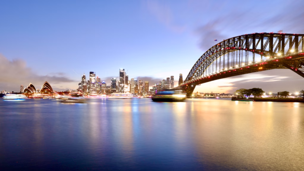 Sydney Opera House, full CBD skyline and Harbour Bridge together in one wide dusk panorama from Jeffrey Street Wharf, Kirribilli, long exposure