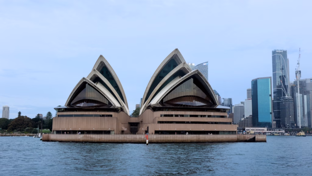 Sydney Opera House viewed from a ferry on Circular Quay, overcast dusk light with the CBD skyline behind