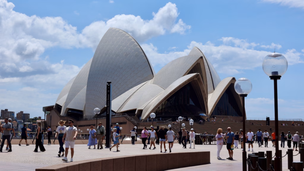 Sydney Opera House sails viewed up close from the forecourt plaza in daytime, crowds of visitors in the foreground