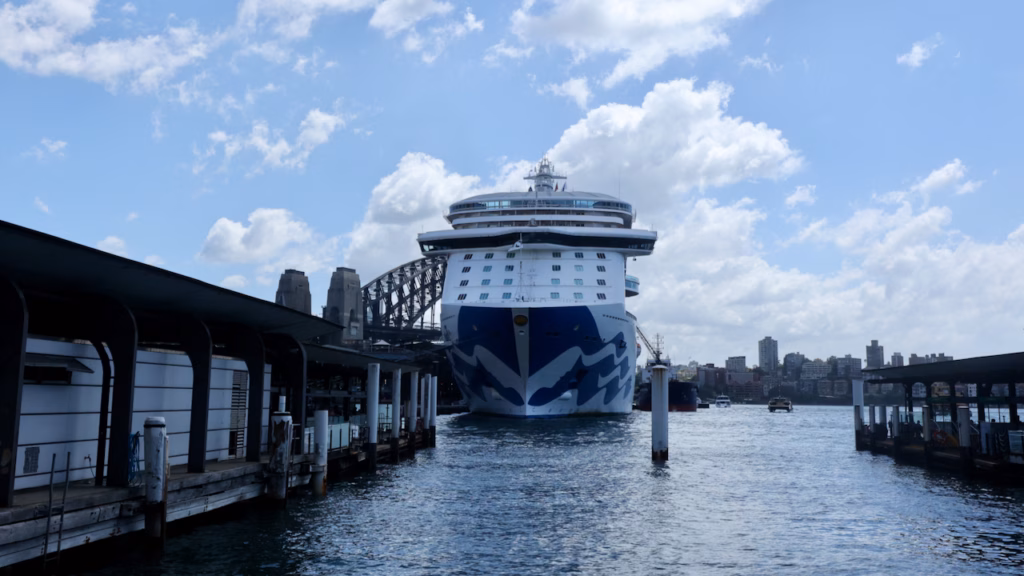 Large cruise ship docked bow-on at the Overseas Passenger Terminal, Circular Quay West, with the Sydney Harbour Bridge visible behind it