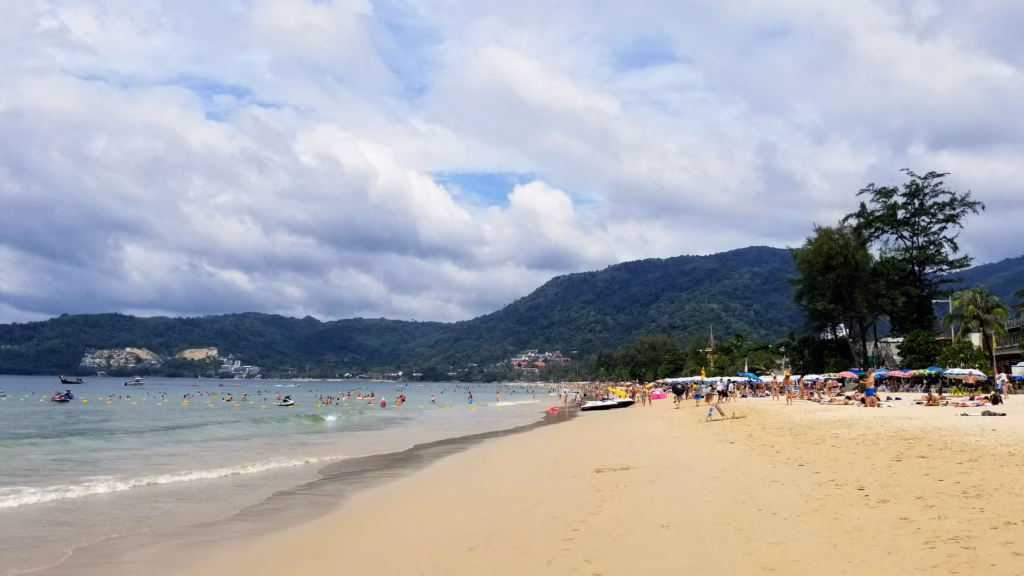 Patong Beach, Phuket, crowded sand and turquoise water backed by green hills