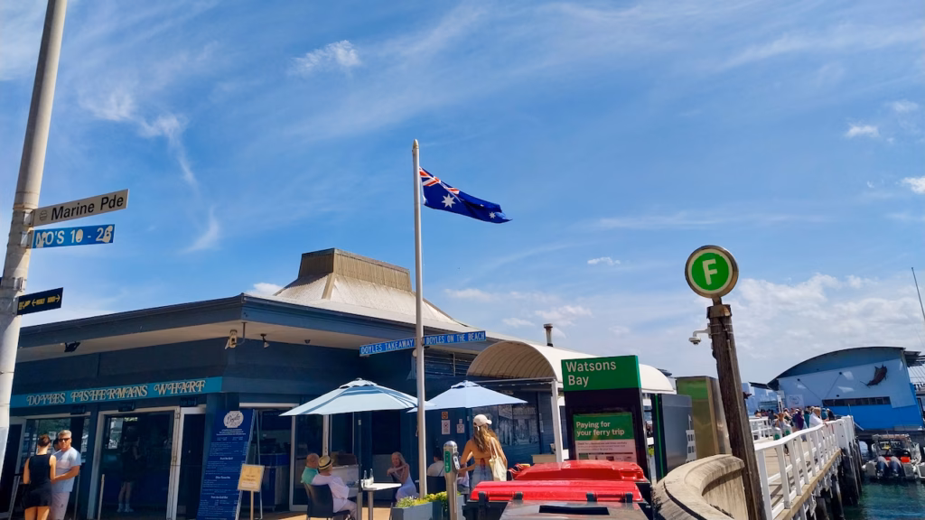 Doyles Fishermans Wharf takeaway beside the Watsons Bay ferry wharf, with Marine Parade street sign and Australian flag