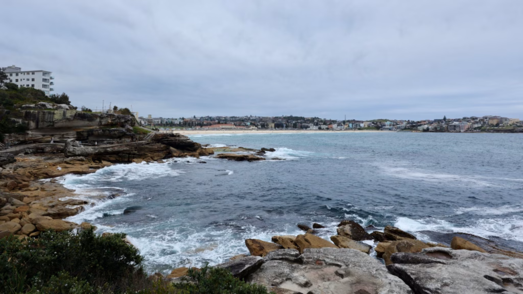 Bondi Beach and the Bondi Pavilion seen across the bay from the sandstone rocks on the Bondi to Coogee walk