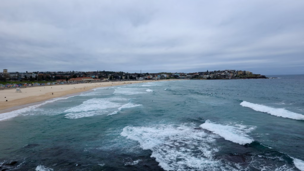 Waves rolling into Bondi Beach seen from the clifftop path near Notts Avenue, with the Bondi Pavilion behind
