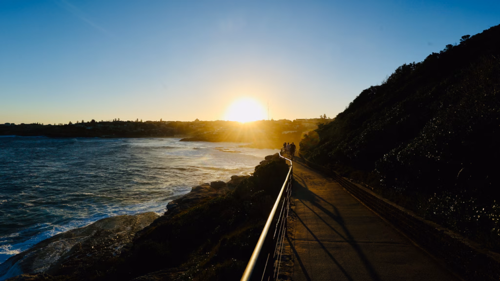 Walkers on the Bondi to Coogee walk heading towards the setting sun near Marks Park